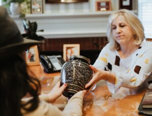 Hilgenfeld Mortuary staff member shows a customer a decorative urn.