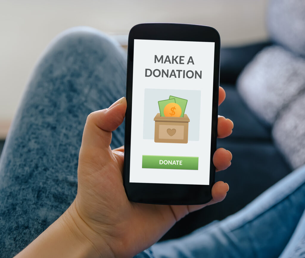 Man with a phone in his hand; "Make a donation" on the screen