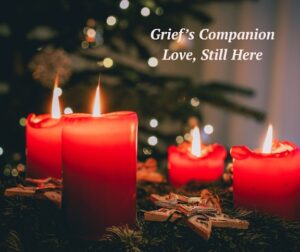 Four candles burn on a table set for the holidays.