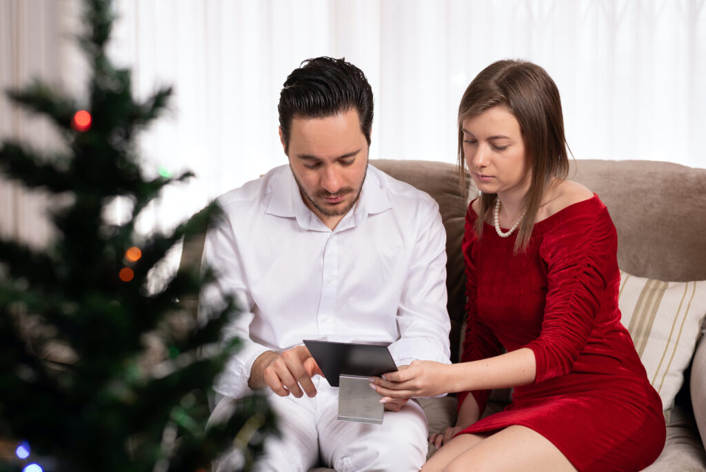 Man and Woman Sitting on Couch and Looking Down at Same Framed Photo