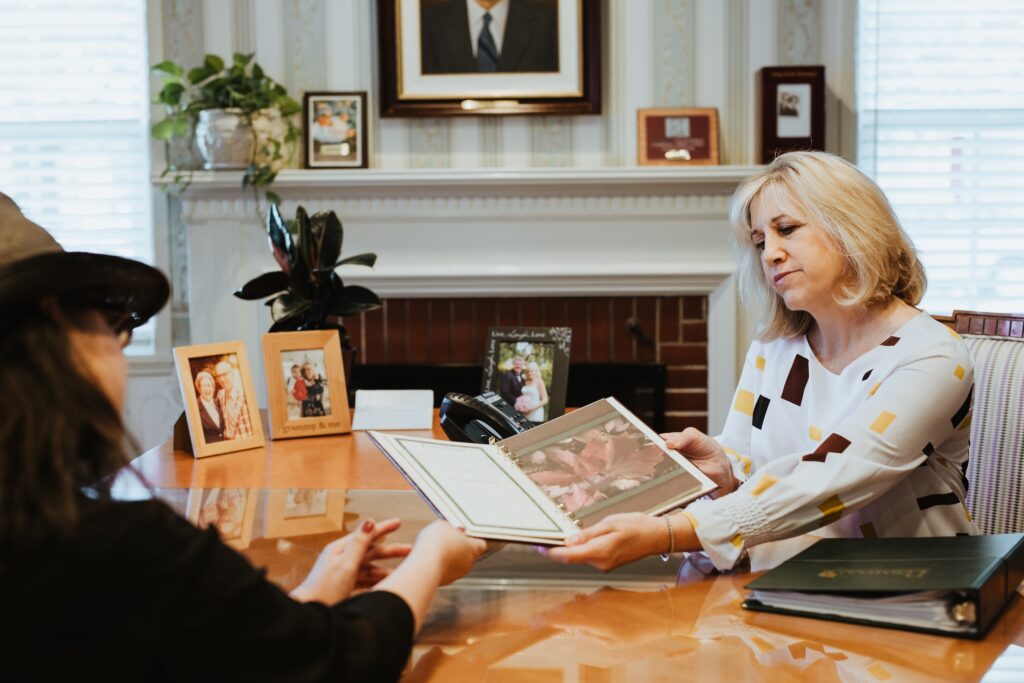 Owner Becky Areias shares a book with a customer at the desk in the main arrangement room.