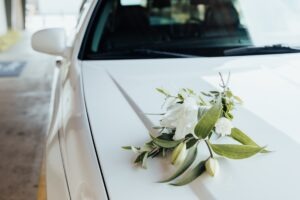 A bouquet of flowers rests on the hood of a white hearse.