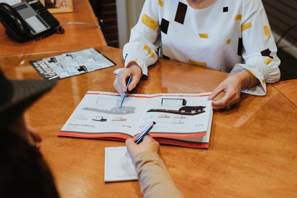 Two individuals looking over a catalog showing casket selections.