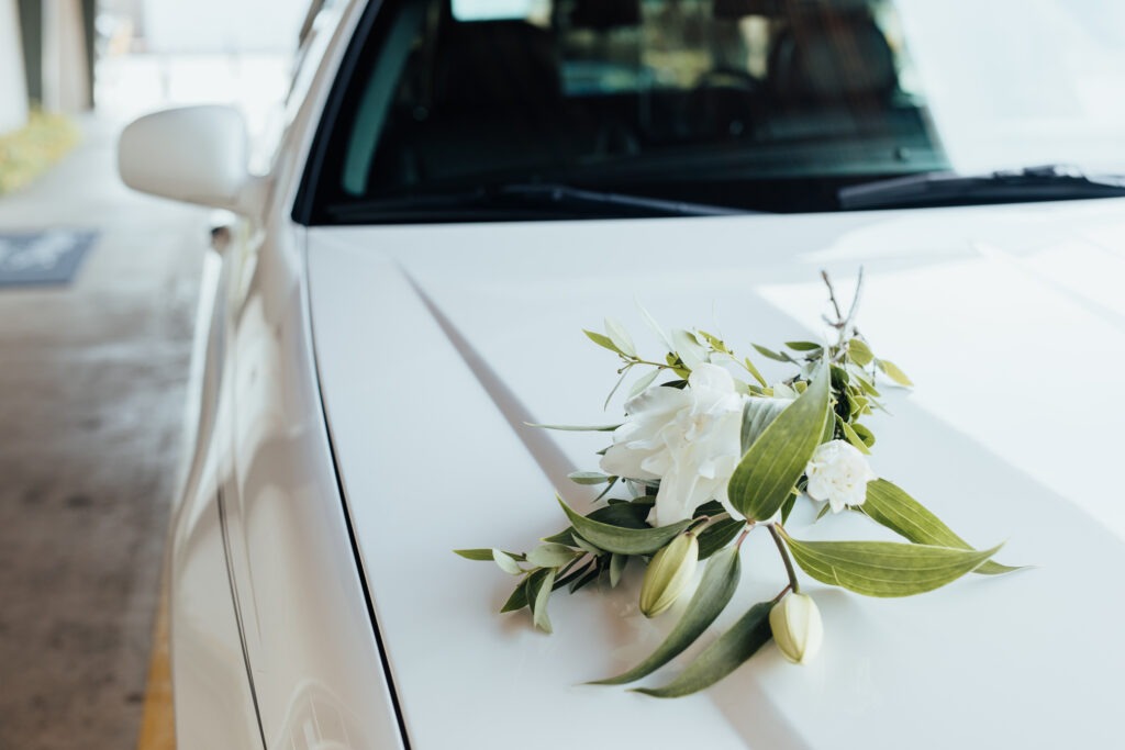 Flowers resting on the hood of a white hearse.