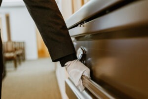 man with pallbearer glove holding onto casket handle